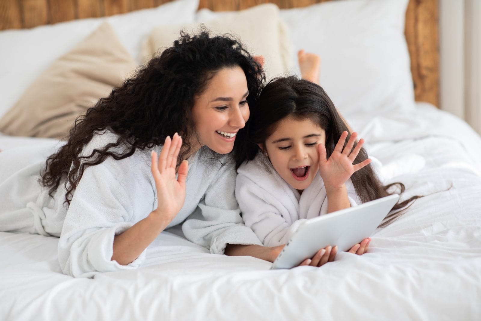 Mom and daughter looking at website on ipad waving