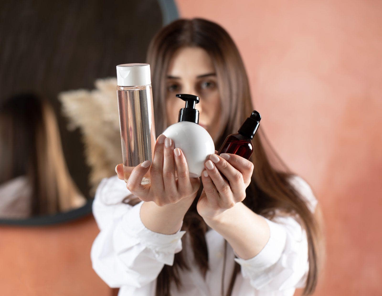 a beautiful brunette girl holds tubes of cosmetic products for hair and skin care. beauty concept.