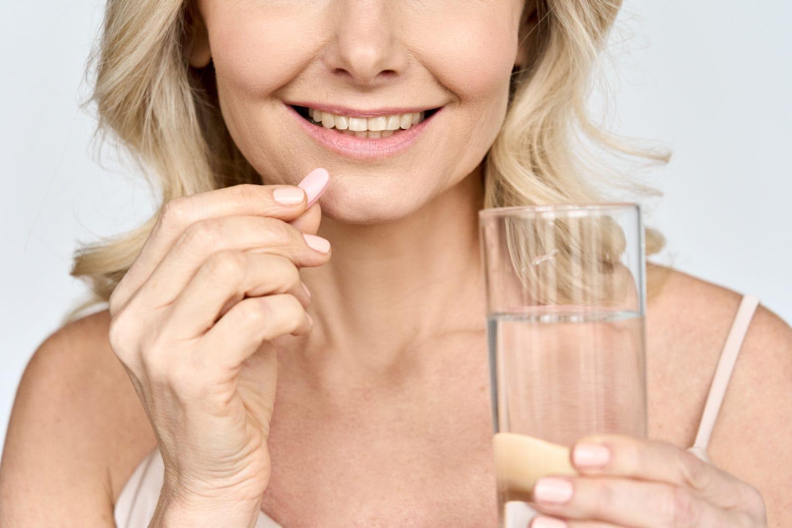 cropped close up portrait of elderly woman taking beauty collagen pills.