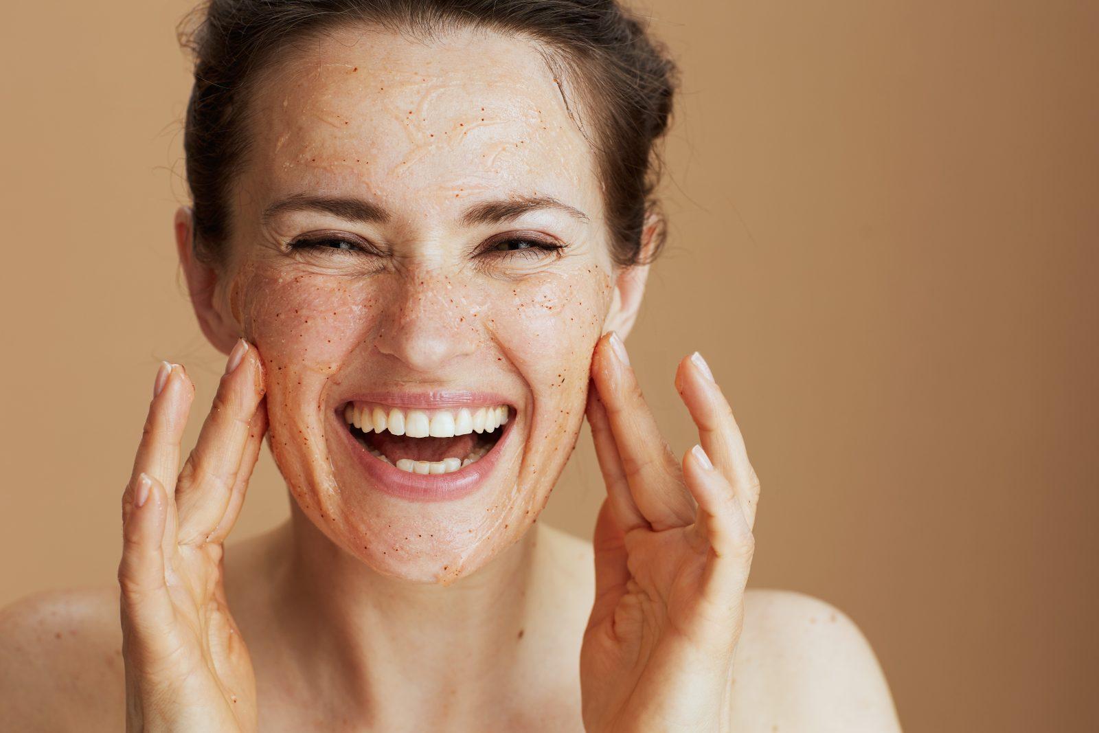 portrait of smiling modern woman with face scrub