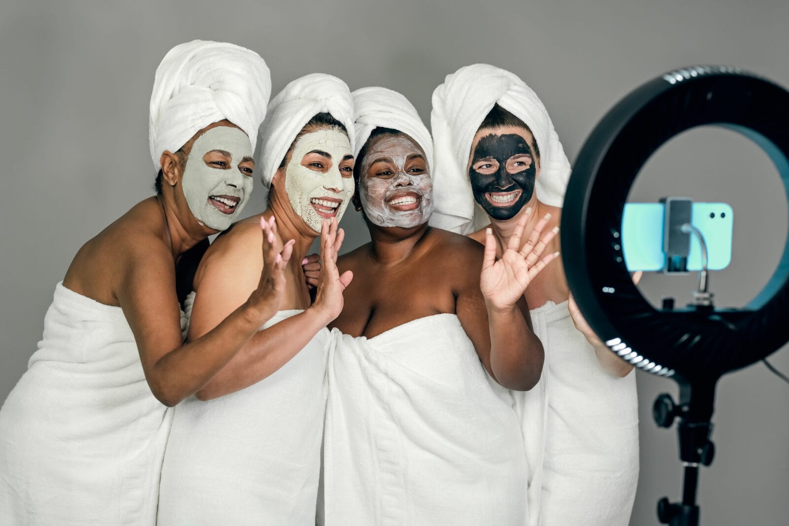 happy multiracial females having skin care spa day while streami