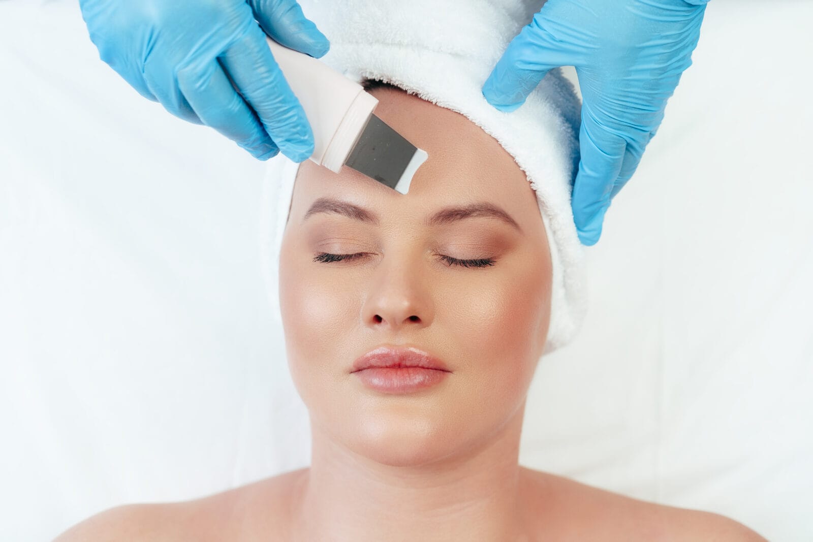 beautiful woman receiving ultrasonic face cleaning in beauty salon